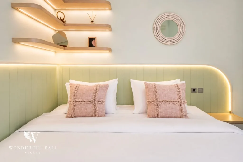 Bedroom with green headboard, pink cushions and shelving at villa in Denpasar, Bali