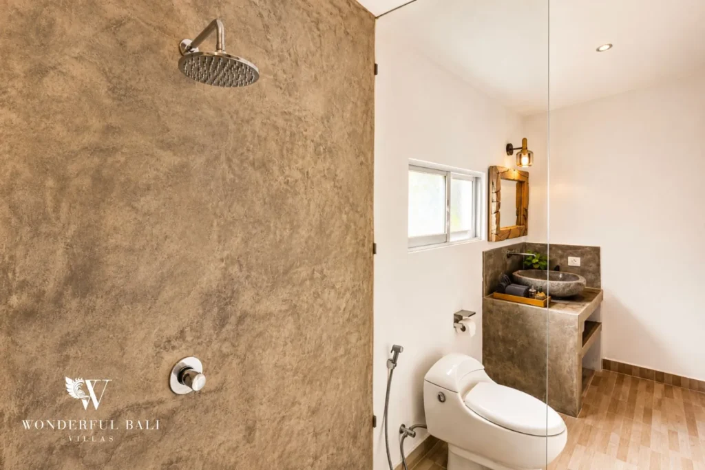 Walk-in rainfall shower with stone walls and concrete finish at villa in Umalas, Bali