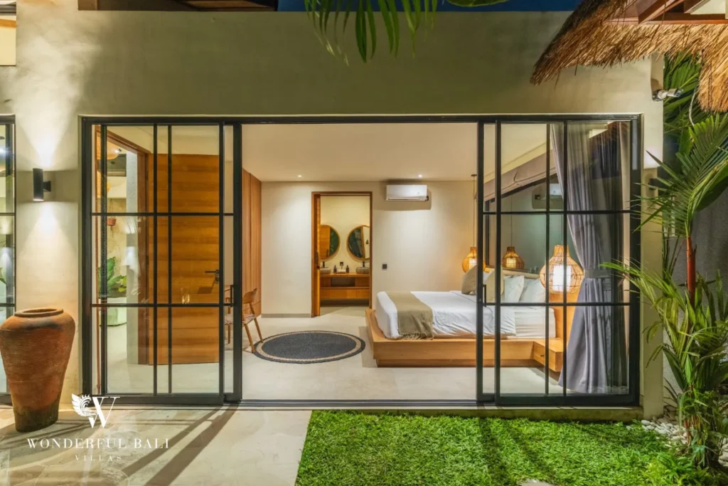 Bedroom with bed and glass doors opening to the garden at villa in Seseh, Bali