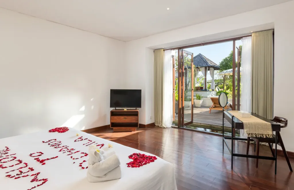 Master bedroom with rose-petal decor opening to the garden at villa in Batu Belig, Bali