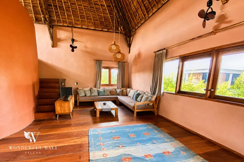 Bedroom lounge with terracotta walls and blue rug at villa in Bumbak, Bali