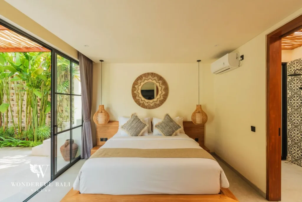 Bedroom with white bed and round mirror at villa in Seseh, Bali