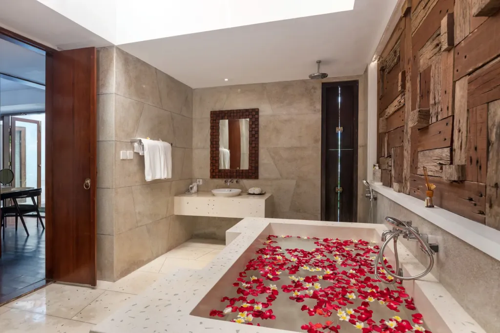Ensuite bathroom with carved timber panel and bathtub at villa in Batu Belig, Bali