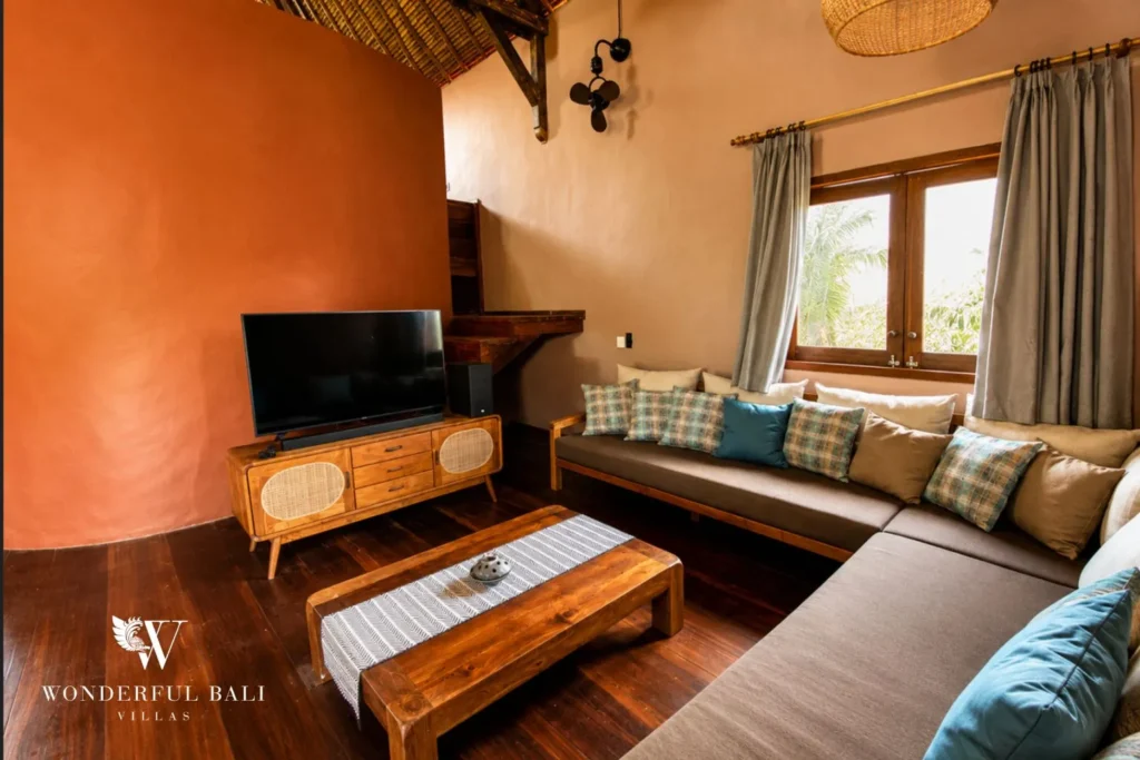 Living area with TV, terracotta walls and sofa at villa in Bumbak, Bali