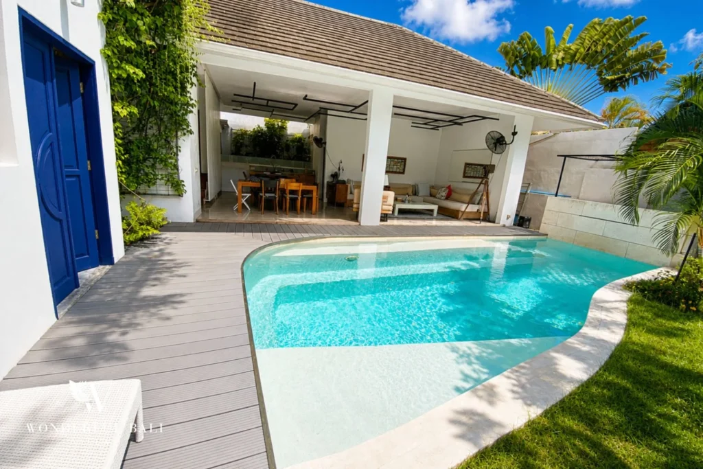 Curved private pool with timber deck and open living pavilion at villa in Umalas, Bali
