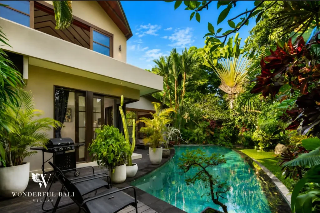 Pool with lush tropical garden and villa exterior at villa in Umalas, Bali