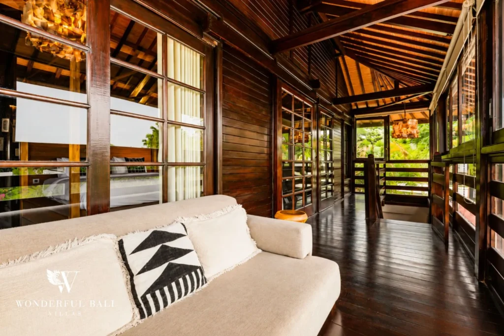 Open-air balcony lounge with white sofa and timber deck view at villa in Umalas, Bali