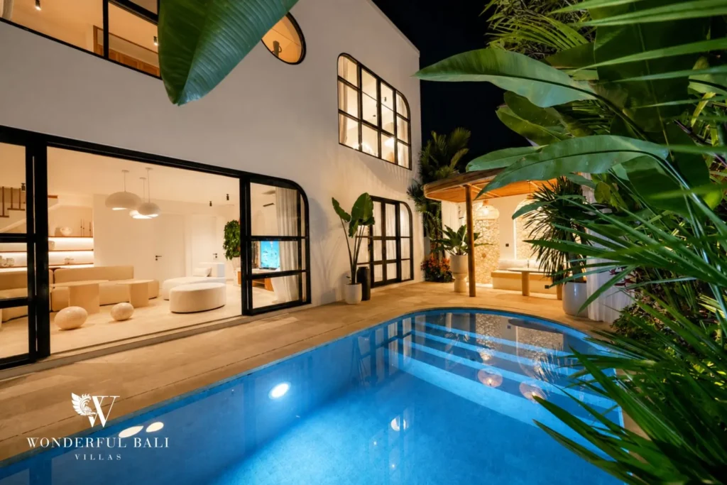 Pool and villa framed by jungle garden and glass walls at villa in Umalas, Bali