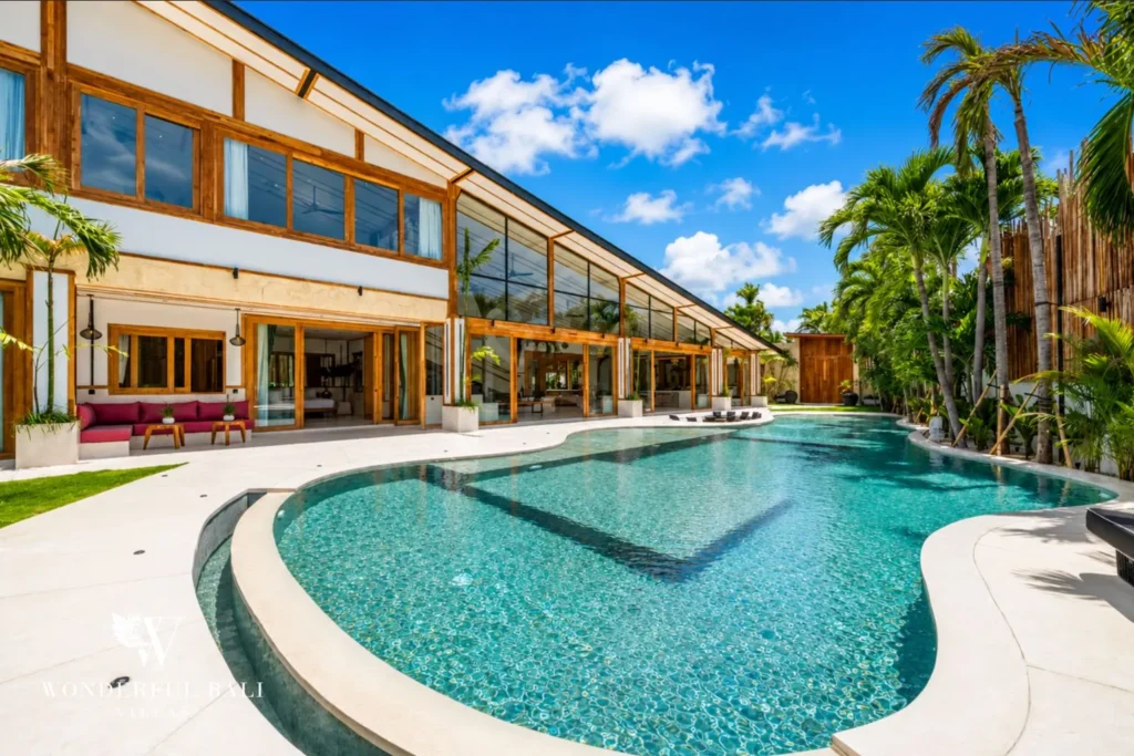 Curved pool with glass-facade villa exterior at family villa in Umalas, Bali