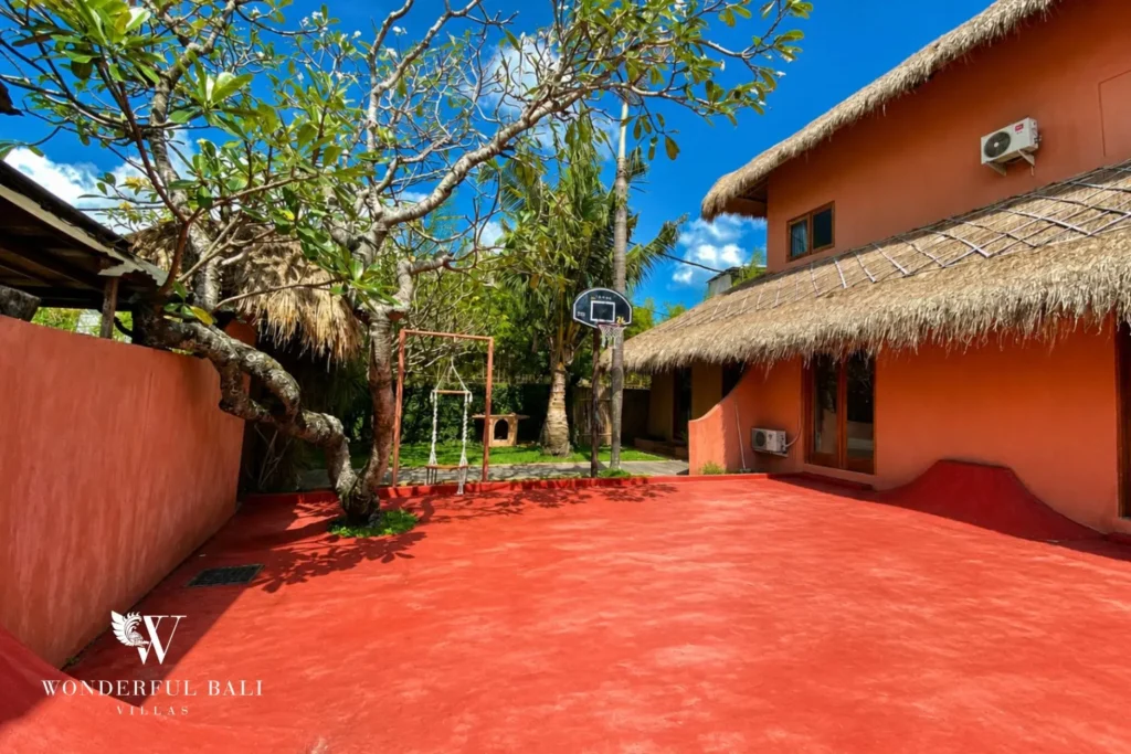 Garden courtyard with a large feature tree and terracotta walls at villa in Bumbak, Bali