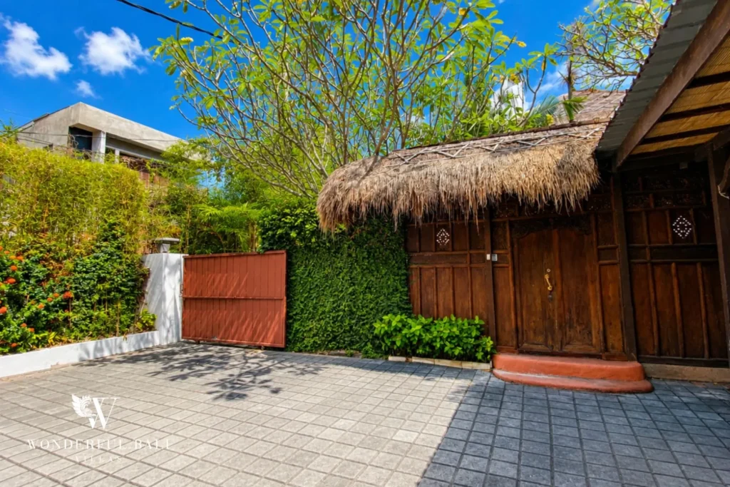 Entrance courtyard with thatched bale and hedging at villa in Bumbak, Bali