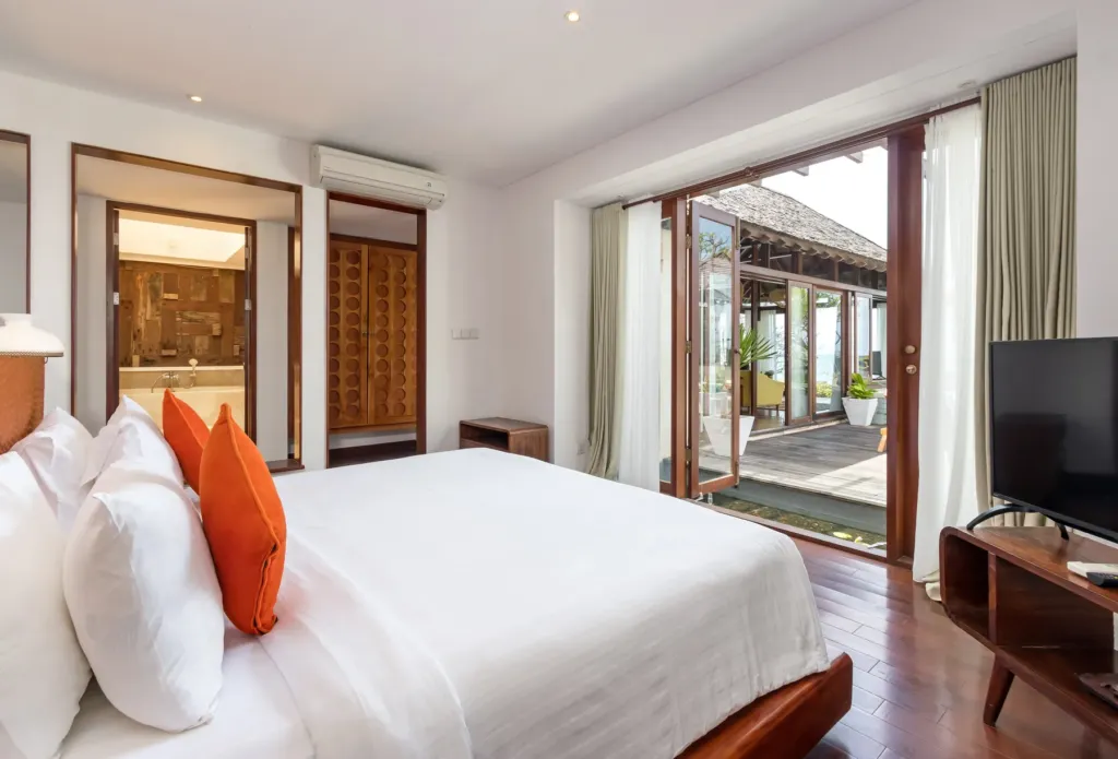 Bedroom with white linens and orange accents at villa in Batu Belig, Bali
