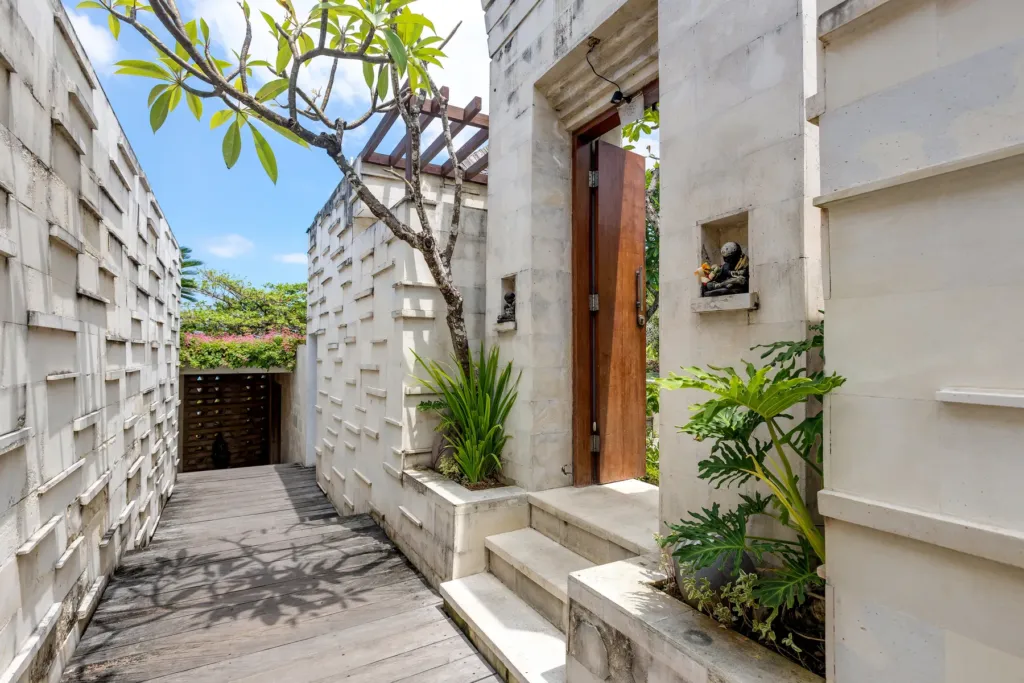 Outdoor courtyard passage with stone wall and plants at villa in Batu Belig, Bali