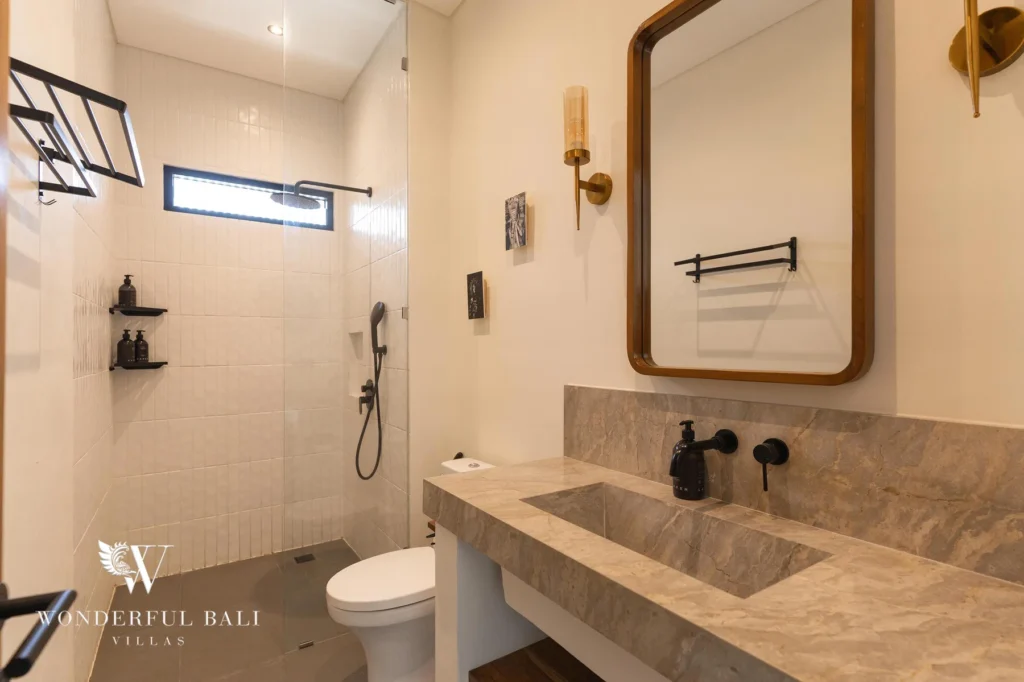 An en-suite bathroom with a marble sink, framed mirror and glass walk-in rain shower at a 2-bedroom villa in Canggu, Bali
