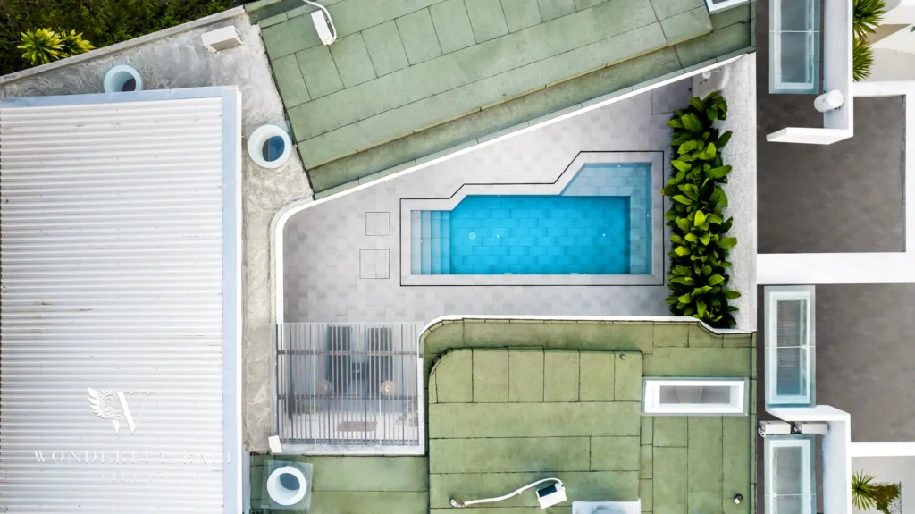 Overhead drone aerial looking straight down at the private pool set within the tiled deck and green rooftops at a 3-bedroom villa in Bingin, Uluwatu, Bali