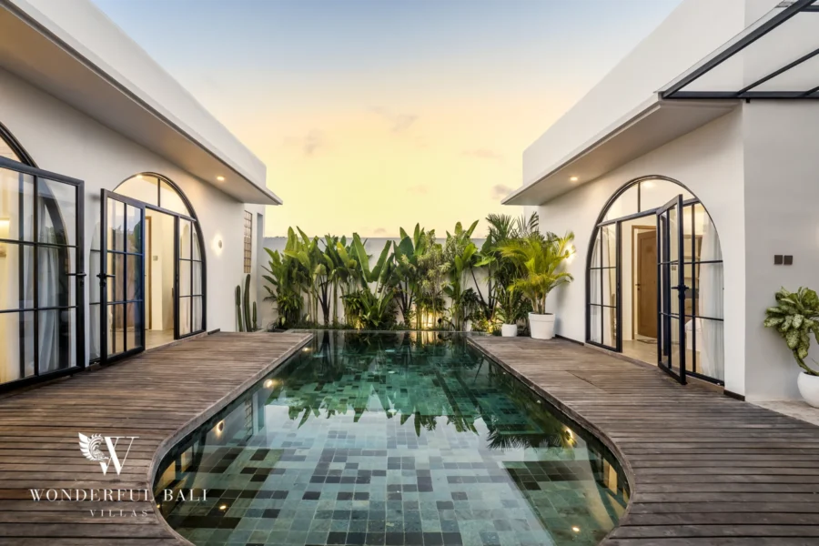 Green-tiled pool at sunset framed by arched glass doors at a 3-bedroom villa in Pererenan, Bali