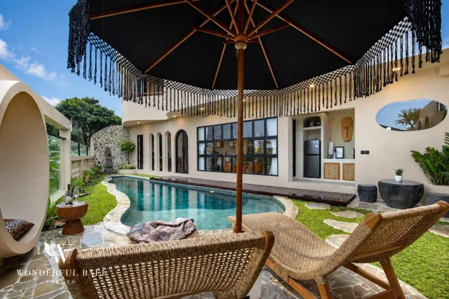 A private pool framed by an umbrella and woven loungers in front of the arched villa facade at a 3-bedroom villa in Pererenan, Bali