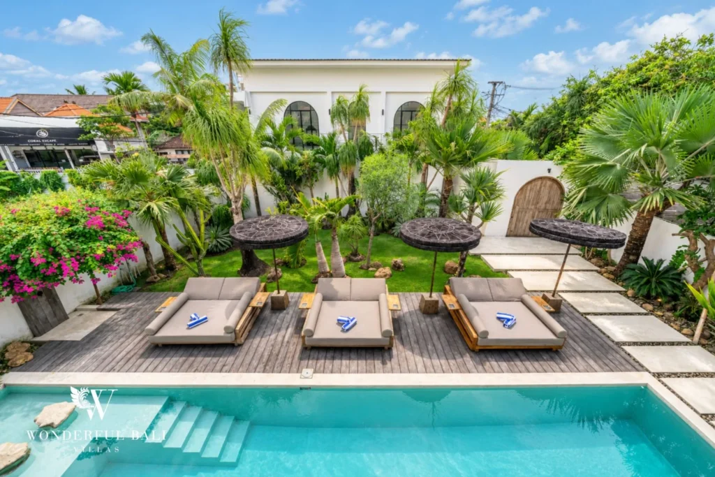Sun loungers under thatched parasols beside the pool at a 4-bedroom villa in Canggu Bali