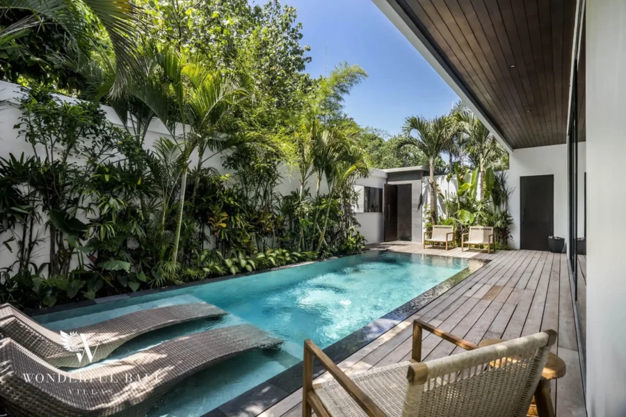A private pool with mosaic-tiled sun loungers and a timber deck framed by palms and greenery at a 3-bedroom villa in Pererenan, Bali