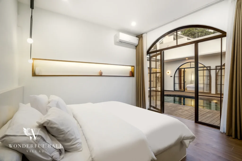Bedroom with arched glass doors opening to the pool at a 3-bedroom villa in Pererenan, Bali