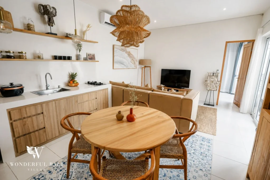 Open kitchen and round teak dining table on patterned floor tiles in a 2-bedroom villa in Cemagi Bali