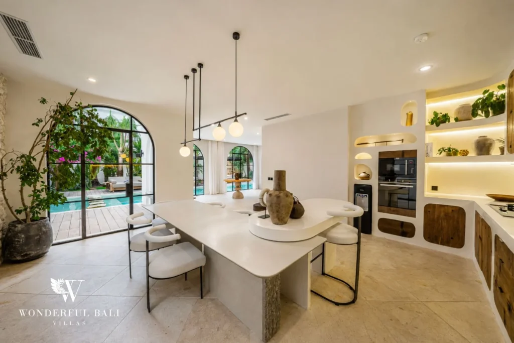 Curved white kitchen island and dining area opening to the pool in a 4-bedroom villa in Canggu Bali