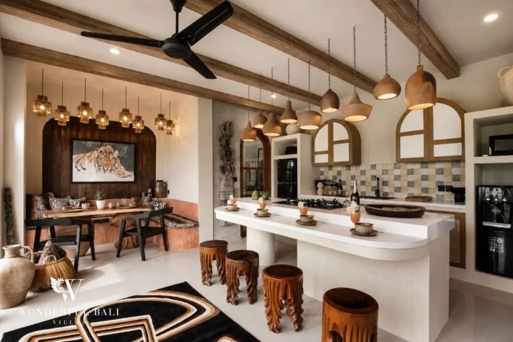 A modern kitchen island with pendant lighting beside a dining nook under a tiger artwork at a 3-bedroom villa in Pererenan, Bali