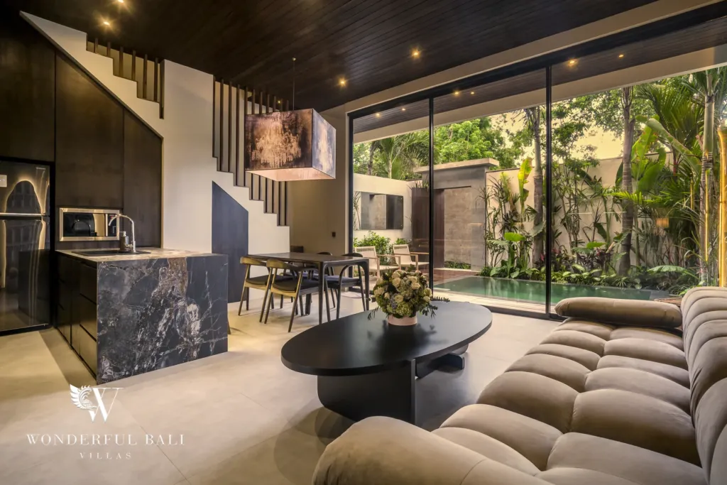 2BR villa for rent in Pererenan — living room, an open living and dining area opening through glass sliding doors to a private pool and tropical garden at a 2-bedroom villa
