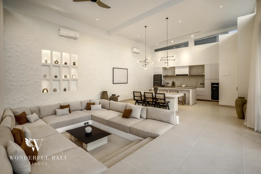 A living room with a trendy sunken sofa, high ceilings and clerestory windows leading to the open kitchen and dining island at a 3-bedroom villa in Bingin, Uluwatu, Bali