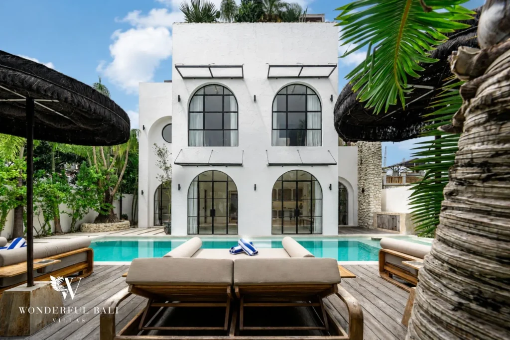 Two-storey white villa facade with arched steel windows above the pool in Canggu Bali
