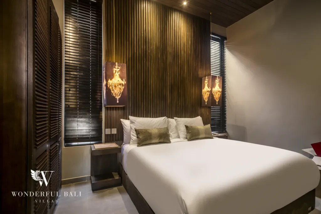 2BR villa for rent in Pererenan — bedroom, a bedroom with a king bed, wood-slat feature wall and ornate chandelier wall sconces at a 2-bedroom villa