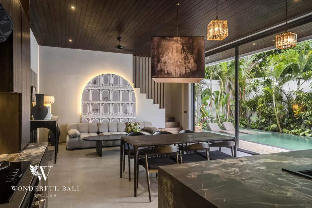 An open-plan living and dining space with lofty wood ceilings, a sofa, dining table and sliding glass doors overlooking the pool at a 3-bedroom villa in Pererenan, Bali