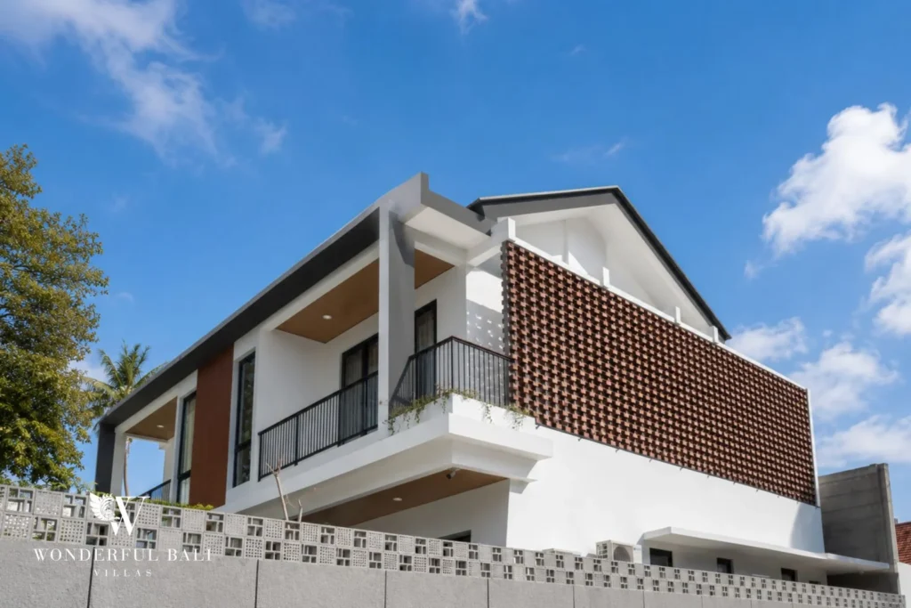 A corner view of the two-storey villa with cantilevered roof, timber accents and a screened balcony against blue sky at a 4-bedroom villa in Pererenan, Bali