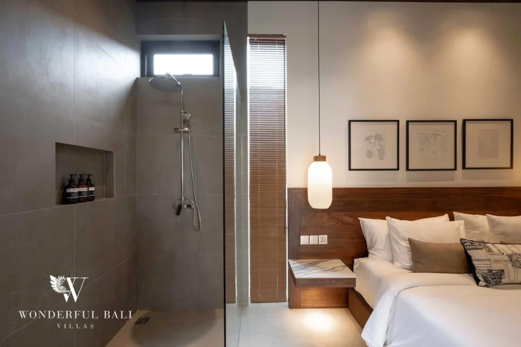 A bedroom with an open grey-tiled walk-in shower beside the bed and framed line art on the wall at a 2-bedroom villa in Canggu, Bali