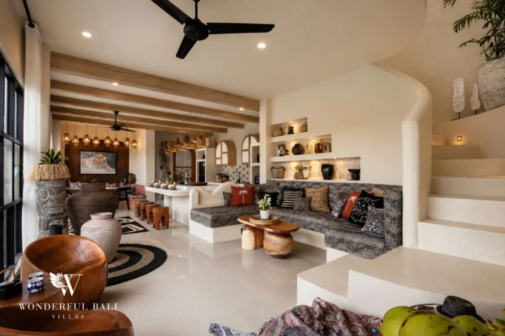 An open-plan living lounge with sofa, sculptural decor and a curved staircase at a 3-bedroom villa in Pererenan, Bali