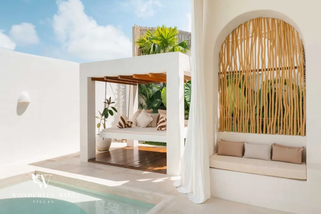 A poolside corner with a white cabana daybed, swing seat and a rattan-screened arched niche seat, at a 2-bedroom villa in Bingin, Uluwatu, Bali
