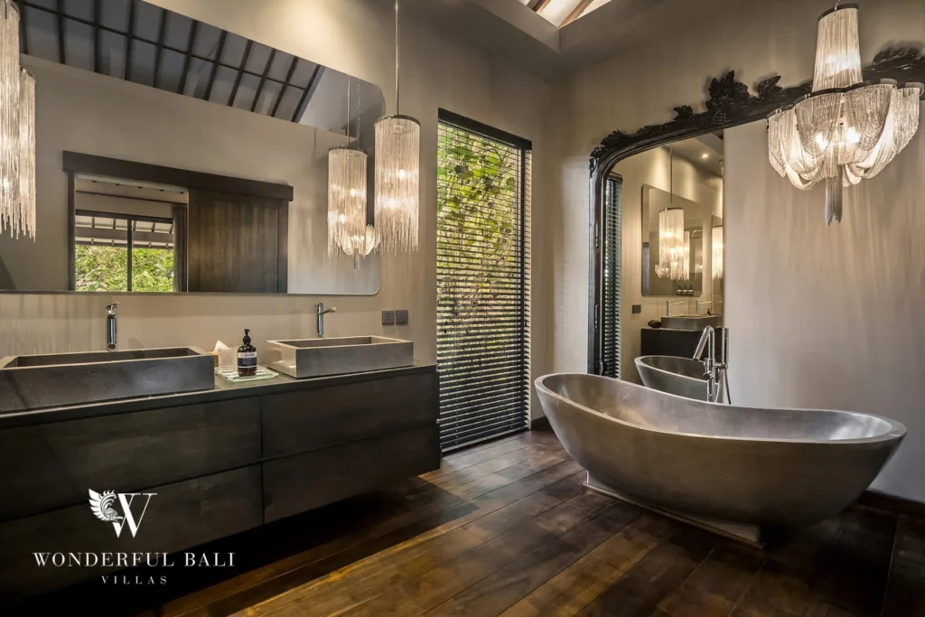 Bathroom with twin stone sinks, freestanding metallic tub and crystal chandeliers at a 2-bedroom villa in Pererenan, Bali