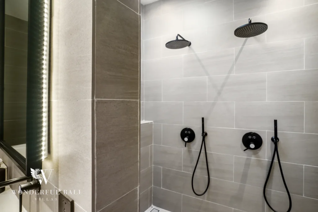 A tiled bathroom with two black rain showers and handheld fixtures at a 3-bedroom villa in Bingin, Uluwatu, Bali