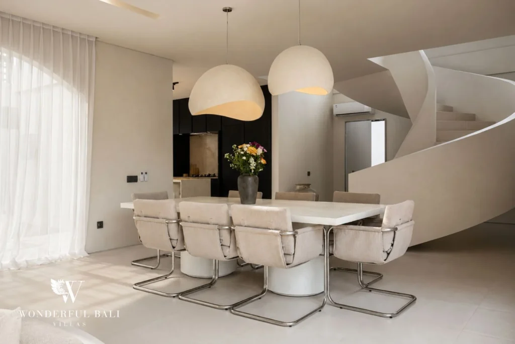 Dining table beside a black-oak open kitchen and spiral staircase at a villa in Umalas, Bali