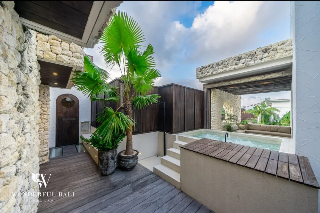 Private jacuzzi on a timber deck beside coral stone walls at a 4-bedroom villa in Canggu Bali