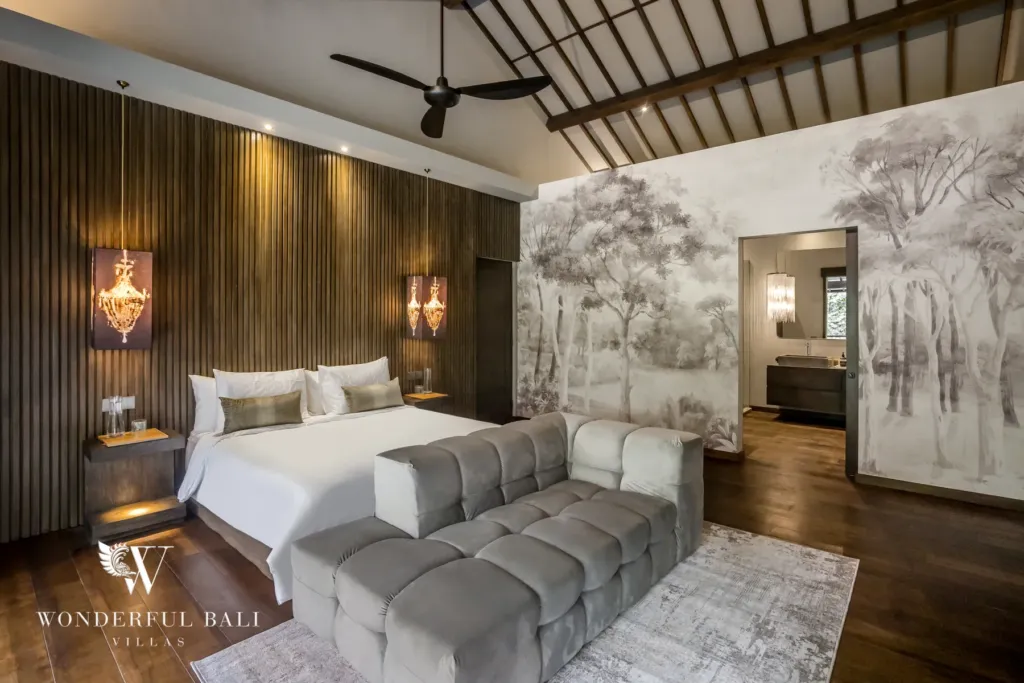 2BR villa for rent in Pererenan — bedroom, a bedroom with a vaulted ceiling, forest-mural wall and an open ensuite bathroom beyond the bed at a 2-bedroom villa