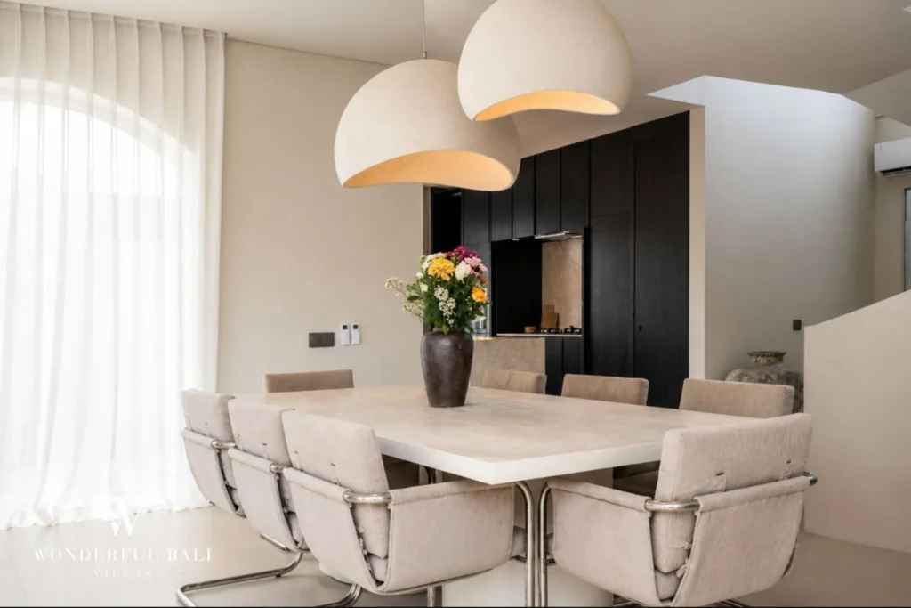 Dining area with sculptural pendant lights and black-oak kitchen at a modern villa in Umalas, Bali