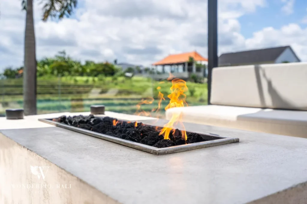 Close-up of a lit stone fire-pit table with rice fields visible in the background at a 5-bedroom villa in Pererenan, Bali
