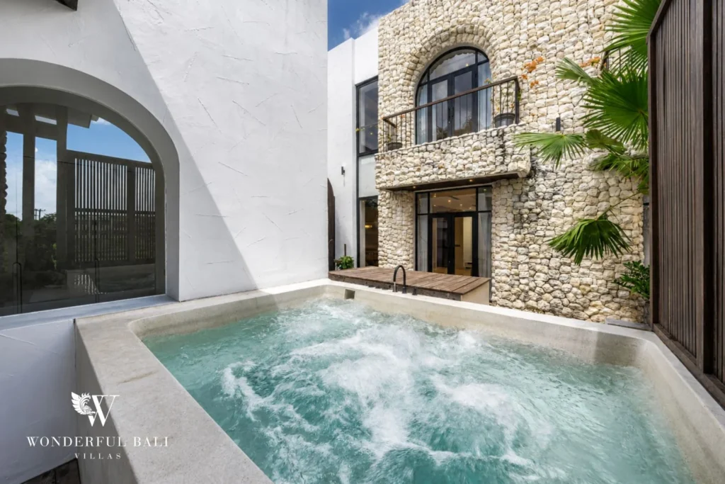 Bubbling private jacuzzi below a coral stone facade at a 4-bedroom villa in Canggu Bali