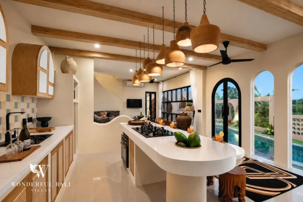 A sleek kitchen island with gas cooktop and rattan pendant lights opening toward the pool at a 3-bedroom villa in Pererenan, Bali
