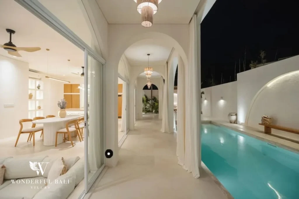 The open-plan dining area and arched corridor lit at night beside the illuminated pool, at a 2-bedroom villa in Bingin, Uluwatu, Bali