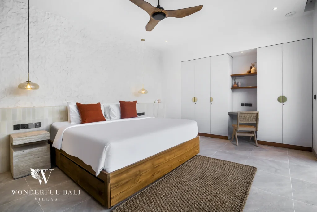 A bedroom with a super-king wooden bed, pendant lights and a built-in wardrobe with a desk nook at a 3-bedroom villa in Bingin, Uluwatu, Bali