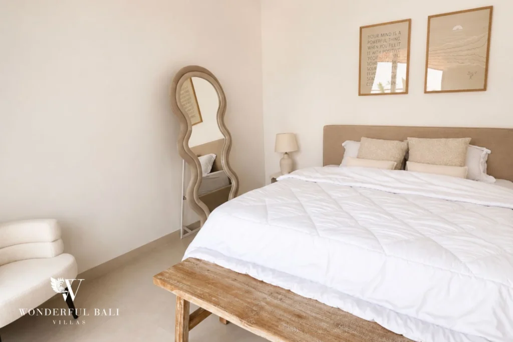 Bedroom with sculpted floor mirror and reclaimed-timber bench in a 2-bedroom villa in Seseh Bali