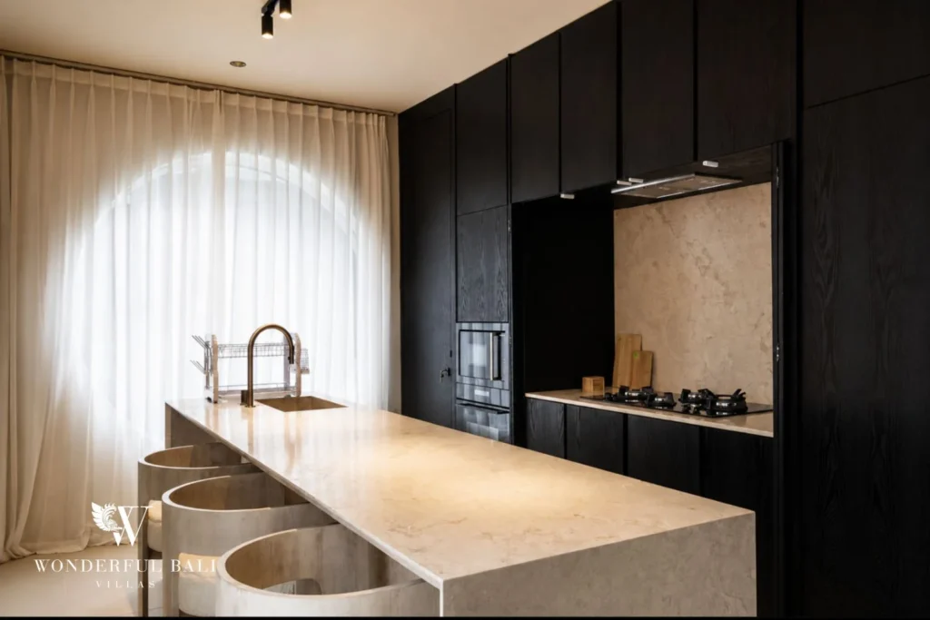 Black-oak kitchen with marble island, gas hob and breakfast seating at a villa in Umalas, Bali
