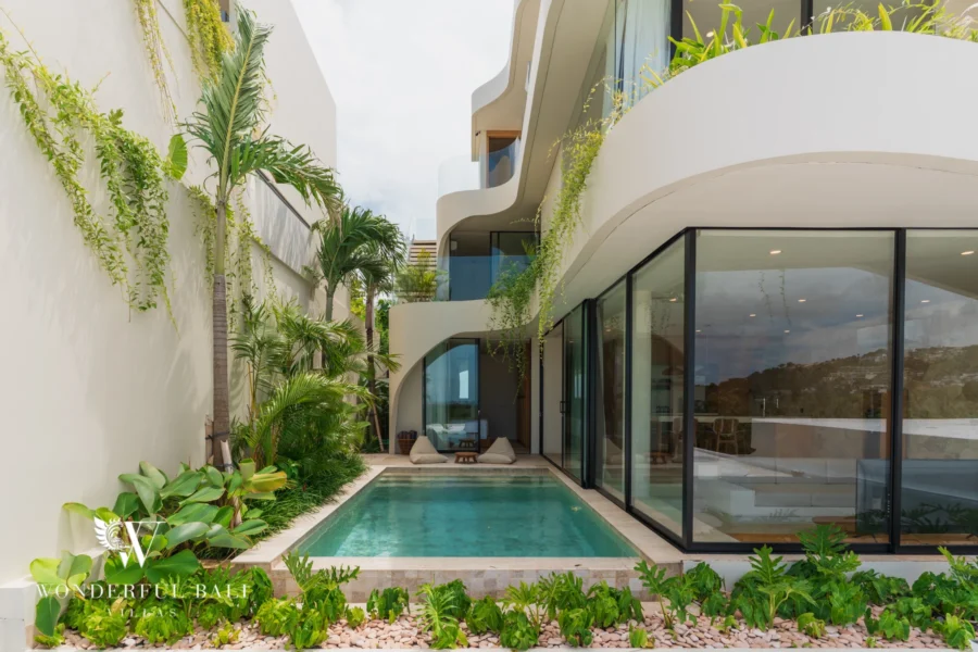 The curved modern exterior of the villa with a private pool, sun loungers and lush tropical planting at a 3-bedroom villa in Bingin, Uluwatu, Bali